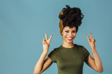 Wall Mural - Portrait of a smiling young woman showing v sign for victory and success with both hands