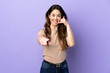 © luismolinero - Woman over isolated purple background making phone gesture and pointing front