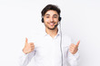 © luismolinero - Telemarketer Arabian man working with a headset isolated on white background giving a thumbs up gesture