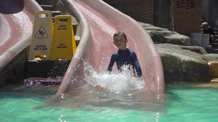 Wall Mural - Slowmotion shot of a little boy on an aqua slides