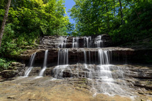 Rivulets Of Falling Water Over Rock Ledges Are Topped By Emerald Green Leaves And A Deep Blue Sky On A Summer Day At Fallsville Falls, A Beautiful Tiered Waterfall Near Hillsboro, Ohio.