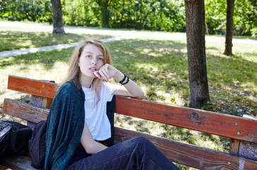 Beautiful attractive woman in white t-shirt posing in the summer park. Active smiling girl resting outdoors