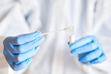 Doctor holding swab test tube for 2019-nCoV analyzing. Coronavirus test. Blue medical gloves and protective face mask for protection against covid-19 virus. Coronavirus and pandemic.