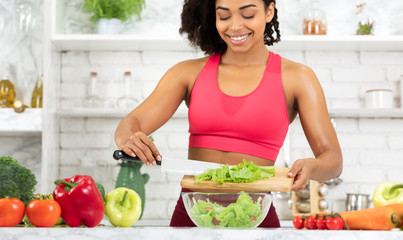 Wall Mural - Beautiful young black girl preparing vegetable salad at home