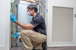 © spatesphoto - HVAC Technician Inspecting Air Filter, Wearing a Face Mask