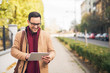 © Jelena - Businessman standing on the street and hold his tablet.