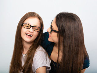 Wall Mural - Young casual smiling mother talking with her happy kid in glasses hugging on light blue background. Closeup studio portrait. Teaching kids staying at home. Online education.