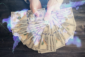 Multi exposure of financial theme drawing hologram and USA dollars bills and man hands. Business concept.