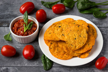 Crispy potato chips on a plate with tomato salsa.