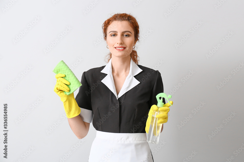 Beautiful young chambermaid on light background