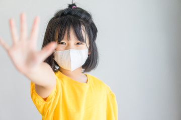 Coronavirus Covid19 Stay at home save lives concept.Little chinese girl wearing surgical face mask show stop hands gesture for stop coronavirus outbreak. Covid-19 coronavirus pandemic symptoms.