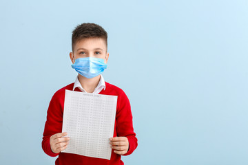 Wall Mural - Pupil in protective mask and with answer sheet for school test on color background. Concept of epidemic