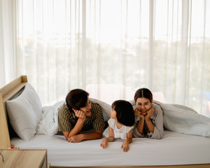 happy family having fun in bed room concept. father,mother and daugther smiling face, kiss love toge