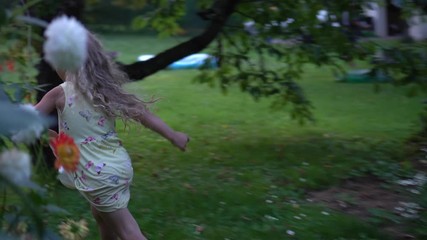 little blond girl with curly hair running through summer garden meadow
