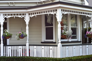 Detail of white vintage villa porch with slate fence and flower pots hanging from ceiling.