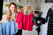 © artiemedvedev - Fashion blogger woman in jeans and turtleneck showing casual colorful shirts on camera. Stylist influencer girl showing trendy clothes filming vlog episode for her channel. Opinion leader sets trends.