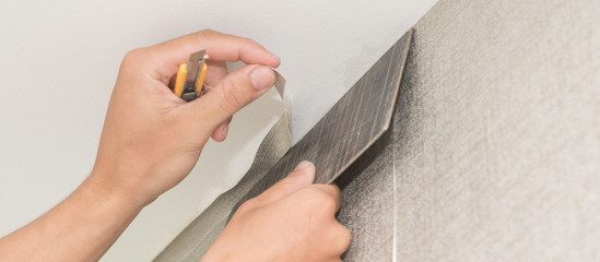 handyman putting up wallpaper on the white walls