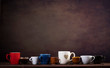 Collection of different cups on wooden table and dark brown background with copy space