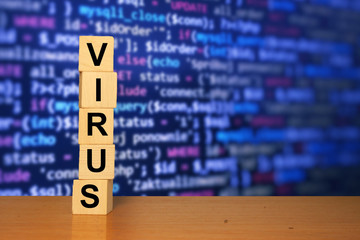 Virus text on wooden cube blocks with blue software developer code screen in background. Coronavirus background. Work from home or remote work.