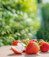 Wall Mural - fresh strawberries on the brown wooden table in garden, red strawberry in farm on natural blur backg