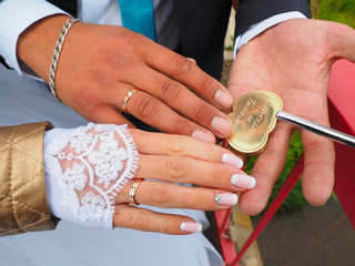 Wall Mural - Hands of the newlyweds with rings, wedding bouquet. Wedding lock, key.  Russia. Russian tradition. Ural