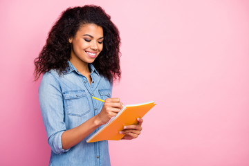 Sticker - Portrait of positive afro american girl write in copy book create diary story wear casual style jeans clothing isolated over pink color background