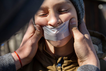 brutal masked man in a hood torments and attacks a teenage