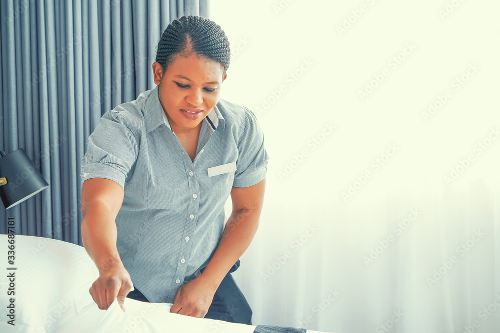 African maid making bed in hotel room. Staff Maid Making Bed. African housekeeper making bed. - obrazy, fototapety, plakaty 