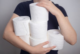 Fototapeta Morze - Woman's hands holding many toilet paper rolls. Panic hoarding, buying for the coronavirus quarantine