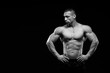 © kiy_lg - Muscular model sports young man in jeans showing his press on a black background. Fashion portrait of sporty healthy strong muscle guy. Sexy torso.  Black and white photography