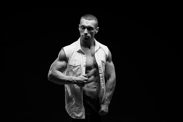 Sexy torso.  Fashion portrait of sporty healthy strong muscle guy.  Muscular model sports young man in jeans showing his press on a black background. Black and white photography
