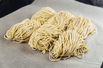 Wall Mural - Nests of asian style handmade raw egg noodle on parchment paper ready to cook, horizontal