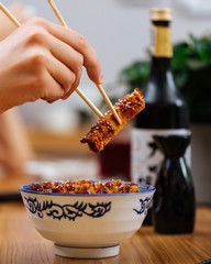 Poster - Eating asian japanese dish fried chicken with katsudon rice in a traditional blue bowl, hand with chopsticks holding piece of chicken side view