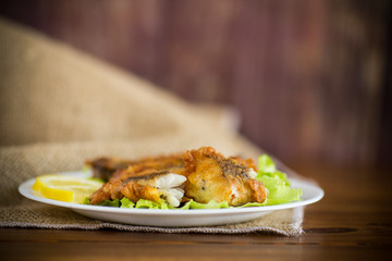 Wall Mural - fried hake fish in batter with lettuce and lemon in a plate