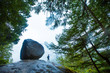 © Emily Polar - Woman hiker stands next to a huge boulder surrounded by trees of the foggy forest in Squamish on the Stawamus Chief hike.