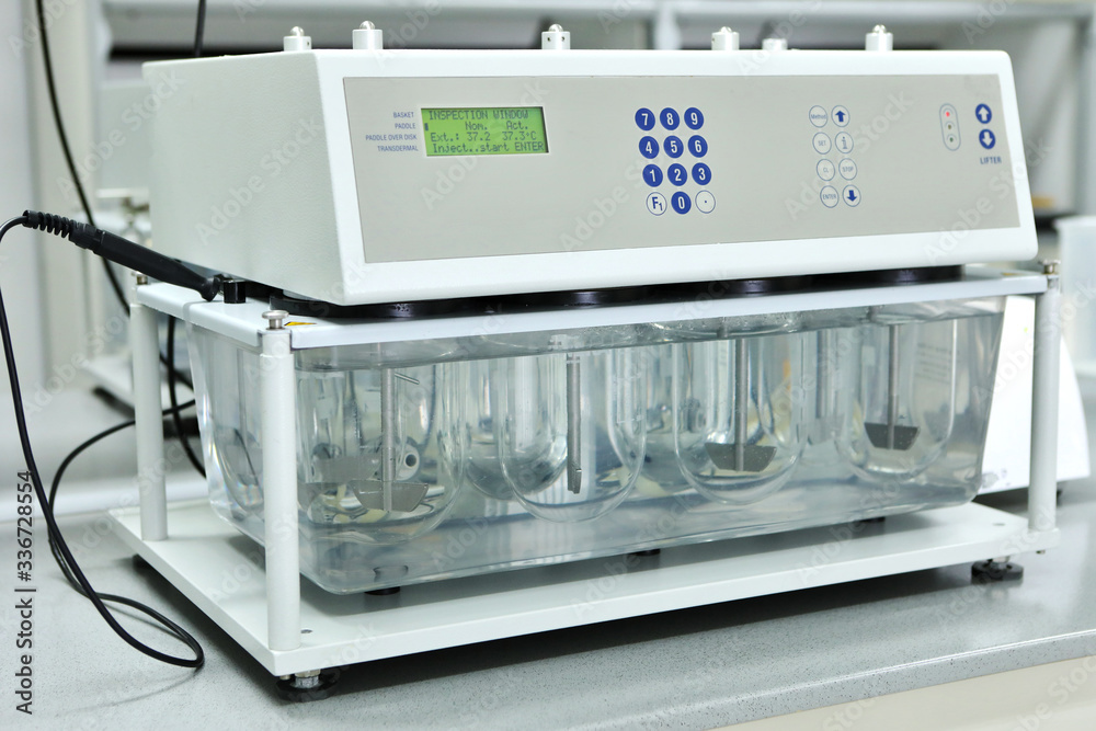 A female chemist conducts solubility tests of tablets and other dosage ...