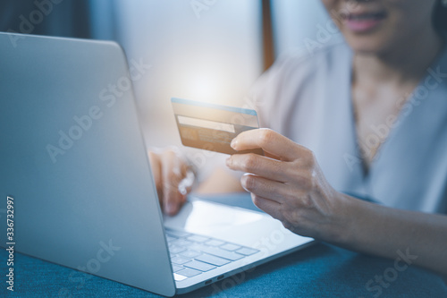 Fotomural Young woman holding credit card and using laptop computer
