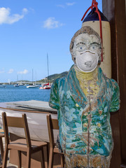 Coronavirus Covid- 19 Pandemic impact on summer travel / tourism: bar mascot at Sint Maarten Yacht Club Bar & Restaurant in the Caribbean wears (used) N95 face mask while business is closed and empty 