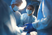 Team Of Professional Surgeons Performing Operation In Clinic