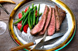 © Andrew Scrivani - Grilled flank steak slices with beans and cherry tomatoes on plate