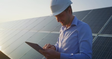 Wall Mural - an young engineer is checking with tablet an operation of sun and cleanliness on field of photovolta