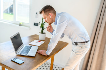 A young businessman in a smart casual uses laptop