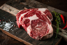 Fresh Raw Beef Rib Eye Steak With Red Pepper And Herbs On A Wooden Background