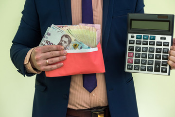 businessman in suit hold calculator and lot of ukraine money, UAH, grivnya, isolated