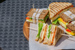 Few different types of club sandwiches on a cutting board on black table. Eating outside, healthy lunch, breakfast or snack. Copy space. 