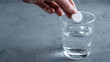 An effervescent aspirin tablet is thrown into a glass of water. Background with space for text.