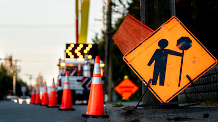 Lane closure on a busy road due to maintenance signs detour traffic temporary street work orange lighted arrow, barrels, and cones.