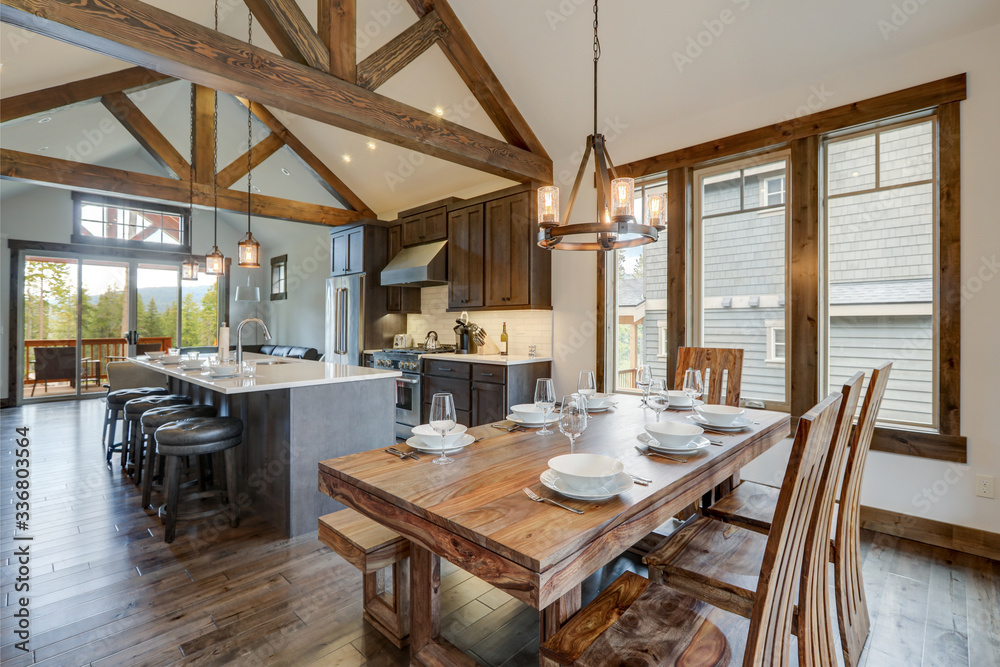 Obraz na płótnie Amazing dining room near modern and rustic luxury kitchen with vaulted ceiling and wooden beams, long island with white quarts countertop and dark wood cabinets. w salonie