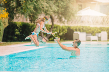 Family of mom and little daughter enjoying summer vacation in luxury swimming pool