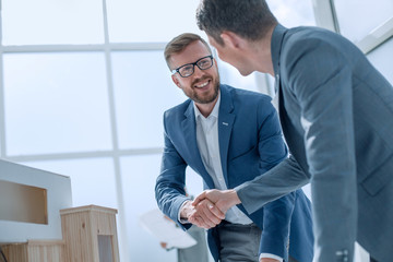 architect and designer shaking hands in creative office.